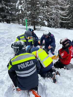 Na stoku narciarskim policjanci udzielają pomocy poszkodowanemu.