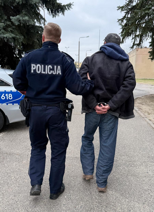 Policjant prowadzi zatrzymanego.