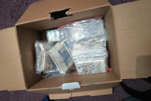 narkotyki porozkładane w samochodzie. Mężczyzna w kajdankach siedzi przy samochodzie. pieniądze rozłożone na stole.