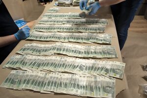 narkotyki porozkładane w samochodzie. Mężczyzna w kajdankach siedzi przy samochodzie. pieniądze rozłożone na stole.