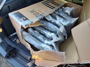 narkotyki porozkładane w samochodzie. Mężczyzna w kajdankach siedzi przy samochodzie. pieniądze rozłożone na stole.