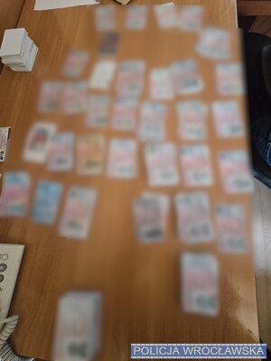 na stole porozkładane karty sim, telefony, w reklamówkach, widać telefony i pieniądze.