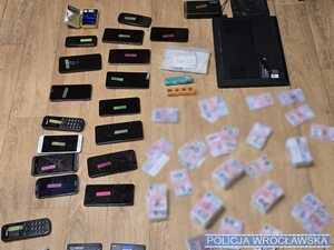 na stole porozkładane karty sim, telefony, w reklamówkach, widać telefony i pieniądze.