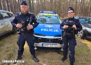 policjanci pozują do zdjęcia stojąc przy radiowozie.