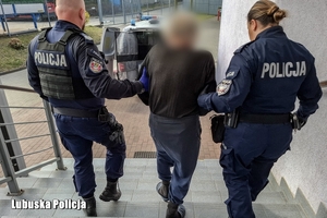 Dwoje policjantów prowadzi zatrzymanego.