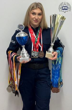policjantka pozuje z pucharem i medalami.