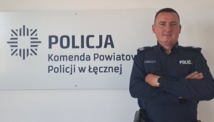 Policjant stoi na tle napisu Policja.