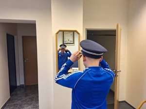 chłopiec wchodzi do komisariatu policji, wita go policjant, chłopiec przymierza stroje policyjne, robi sobie zdjęcia.