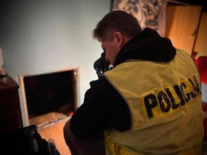 Technik z łódzkiej komendy robi zdjęcie wejścia do ukrytego pomieszczenia.