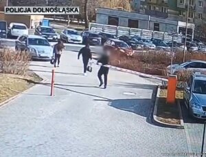 Mężczyzna ciągnie szlaban niszcząc go - stop klatka z monitoringu.