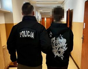 Policjant prowadzi zatrzymanego.