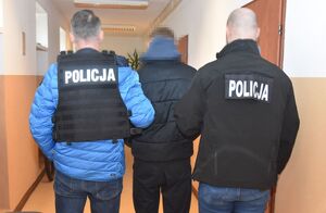 Policjant prowadzi zatrzymanego.