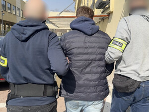 Dwaj policjanci prowadzą zatrzymanego.