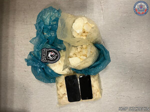 zabezpieczone narkotyki w foliowych workach. obok leżą dwa telefony.