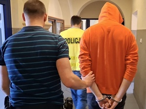 policjant prowadzi zatrzymanego.