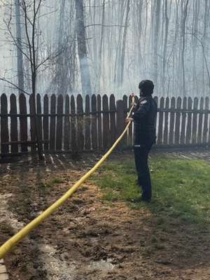 Policjant gasi pożar z węża.