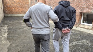 policjanci prowadzą zatrzymanego.