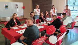 mężczyźni i kobiety siedzą przy stole i wypełniają ankiety.