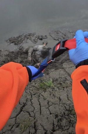 Mężczyzna wyciągany z rzeki za pomocą liny holowniczej.