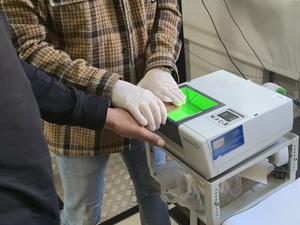 Nieumundurowany policjant, który pobiera od zatrzymanego ślady daktyloskopijne.