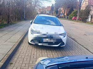 Biały samochód stojący przy krawężniku.