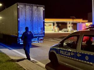 Odzyskana ciężarówka a za nią na drodze policjant i policyjny radiowóz.