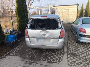 Policjanci prowadzą zatrzymanych. Kable porozkładane na ziemi w pudełkach i kartonach.