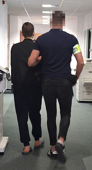 policjanci prowadzą zatrzymanego.