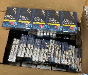 policjanci prowadzą zatrzymanego. Papierosy bez akcyzy leżą porozkładane w kartonach.