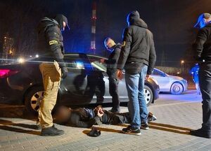 Pora nocna. Na ziemi leży skuty kajdankami mężczyzna, a nad nim stoi czterech nieumundurowanych policjantów.