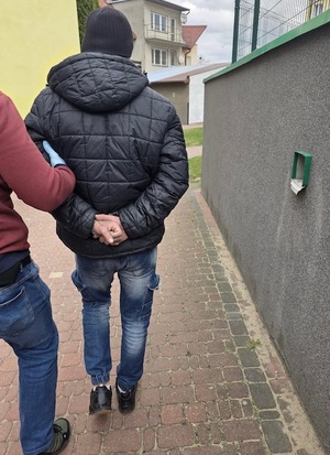 policjant prowadzi zatrzymanego.