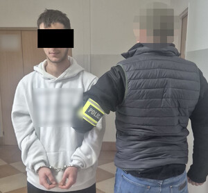 Policjant z zatrzymanym mężczyzną zakutym w kajdanki.