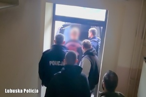 korytarz, policjanci prowadzą zatrzymanego.