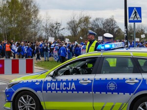 Policjanci ruchu drogowego stoją obok oznakowanego radiowozu.