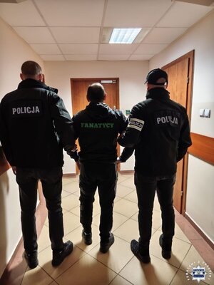 Zatrzymany pseudokibic prowadzony przez policjantów.