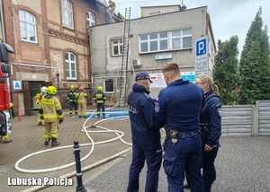 Policjanci i strażacy obok budynku, w którym wybuchł pożar.