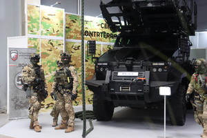 Zdjęcie przedstawia pojazd typu Lekki Transporter Opancerzony TUR VI oraz czterech funkcjonariuszy Centralnego Pododdziału Kontrterrorystycznego Policji „BOA”