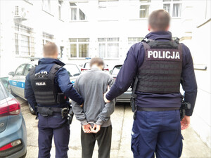Dwaj policjanci prowadzą zatrzymanego.