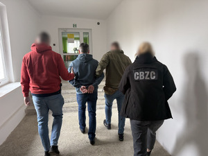 policjanci prowadzą zatrzymanego.