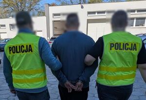 dwóch policjantów prowadzi zatrzymanego.