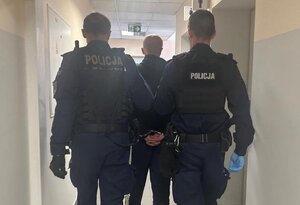 policjanci prowadza zatrzymanego.