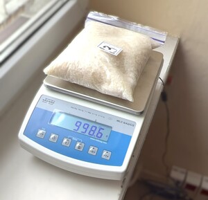 policjanci prowadza zatrzymanego, Na stole w workach plastikowych porozkładane marihuana, kryształ.