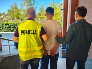 dwóch policjantów prowadzi zatrzymanego.