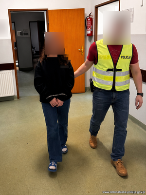 Policjant prowadzi zatrzymanego.