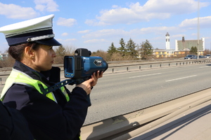 Zdjęcie przedstawia funkcjonariusza Policji z laserowym miernikiem prędkości