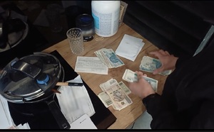 Policjant liczy zabezpieczone pieniądze.