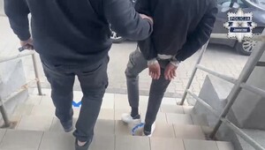 Policjant prowadzi zatrzymanego.