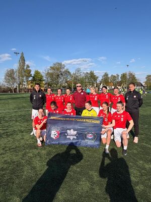 Reprezentacja kobiet pozuje do zdjęcia na boisku.