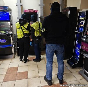 Policjant i funkcjonariusze służby celno skarbowej przy automacie do gier.