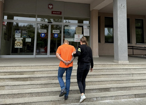 Policjantka prowadzi zatrzymanego.